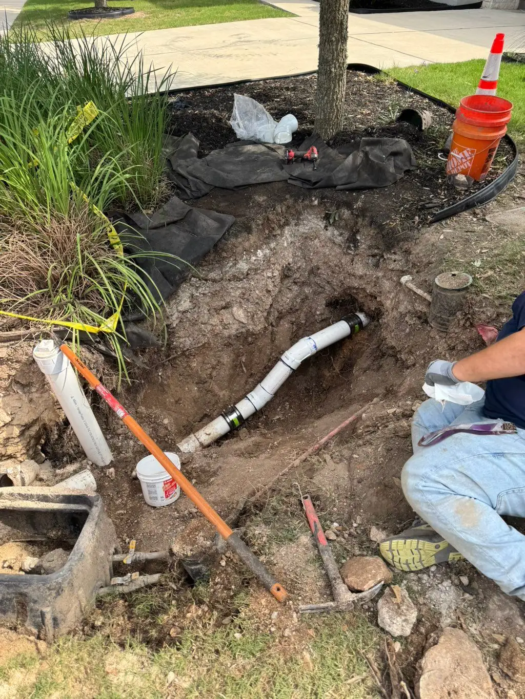 Open trench with a repaired outdoor water line and concrete pavers beside it